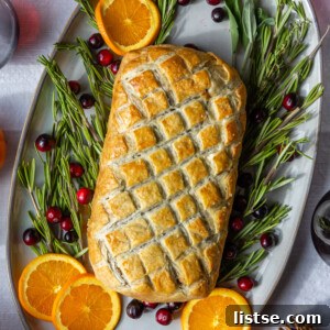 vegetarian wellington on a large platter surrounded by rosemary, orange, and fresh cranberries