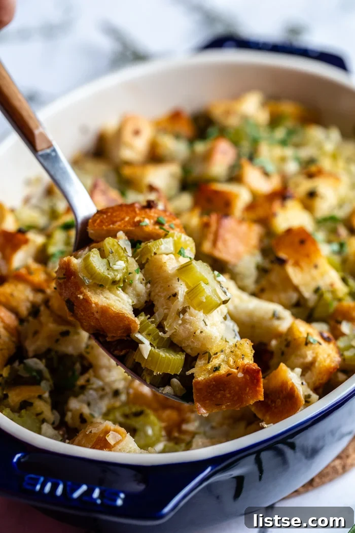 Foolproof Vegan Holiday Stuffing 4 Close-up of baked vegan stuffing in a casserole dish, showcasing its golden-brown, crispy top and tender, moist interior, garnished with fresh herbs.