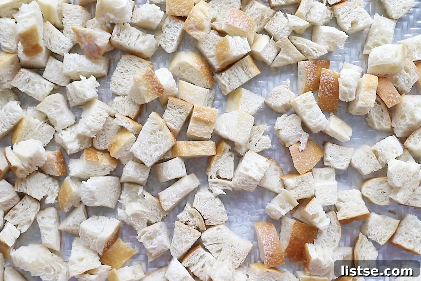 Foolproof Vegan Holiday Stuffing 5 Cubed sourdough bread spread out on a sheet pan, perfectly arranged and ready for toasting to achieve ideal crispness for vegan stuffing.