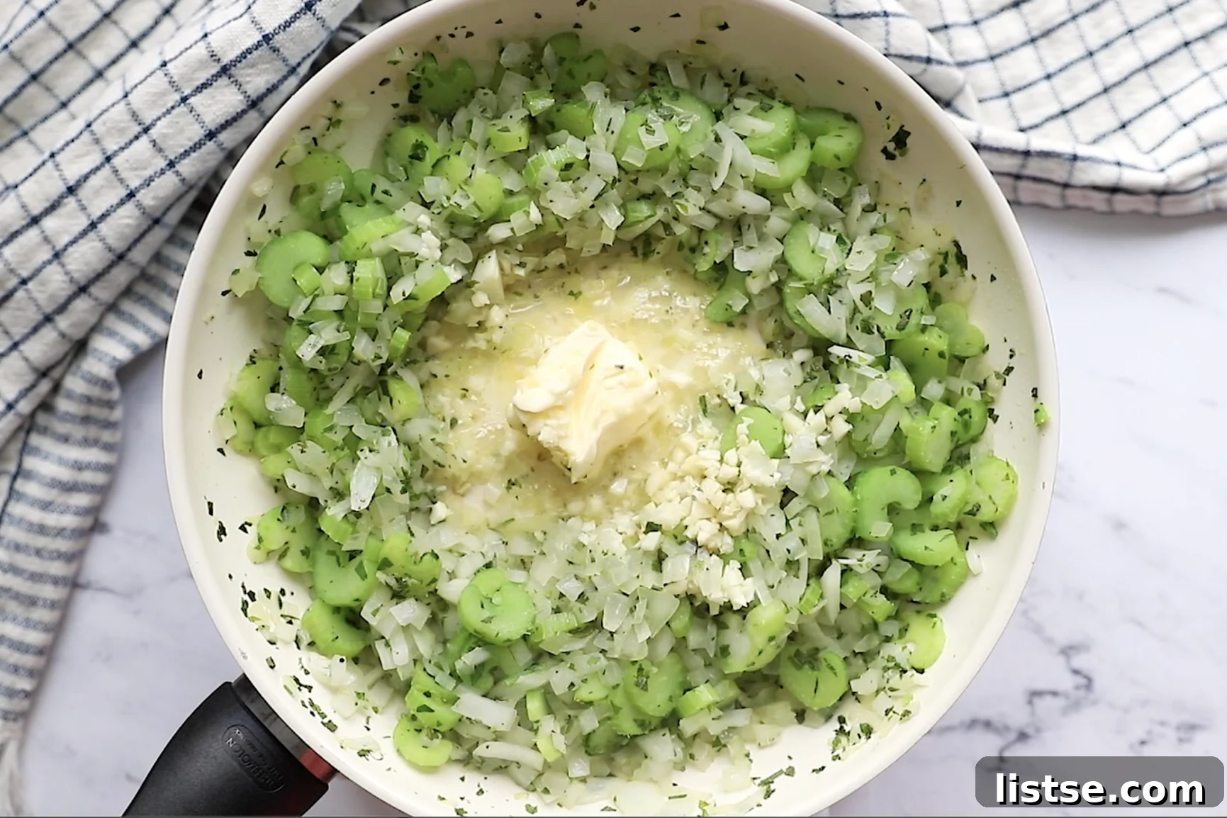 Foolproof Vegan Holiday Stuffing 6 Diced onions and celery simmering in melted vegan butter and olive oil in a large skillet, accompanied by fresh herbs and minced garlic, filling the kitchen with fragrant aromas.