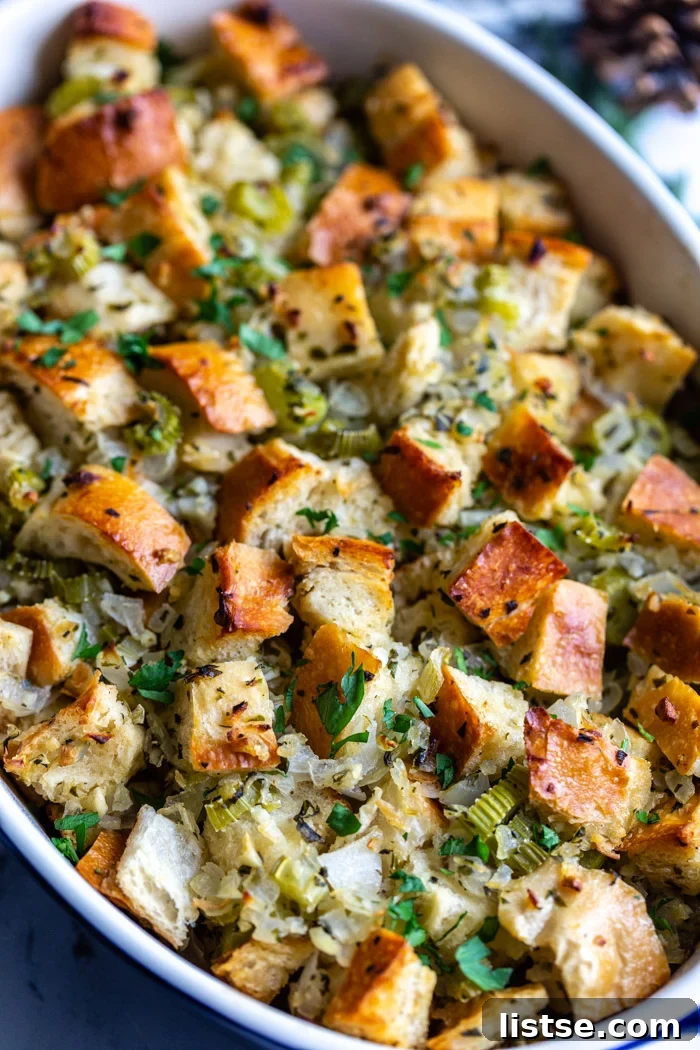 Foolproof Vegan Holiday Stuffing 9 A generous serving of perfectly baked vegan stuffing, garnished with a sprig of fresh sage, resting on a white plate ready to be savored.
