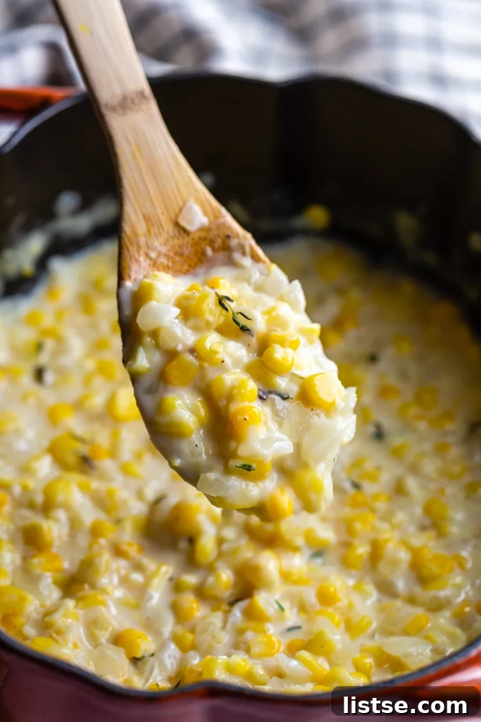 Velvety Vegan Creamed Corn 3 A pot of rich vegan creamed corn with a wooden spoon scooping up a generous portion, showing its smooth, creamy texture.