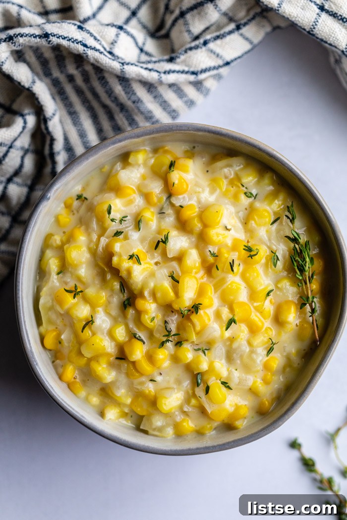 Velvety Vegan Creamed Corn 6 A light blue bowl filled with delicious vegan creamed corn, garnished with fresh thyme, ready to be served.