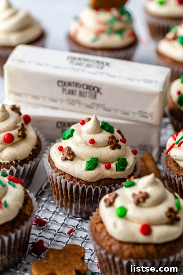 Spiced Gingerbread Cupcakes 2 Delicious vegan gingerbread cupcakes topped with gingerbread men sprinkles, with Country Crock Plant Butter sticks in the background, showcasing the perfect holiday treat.