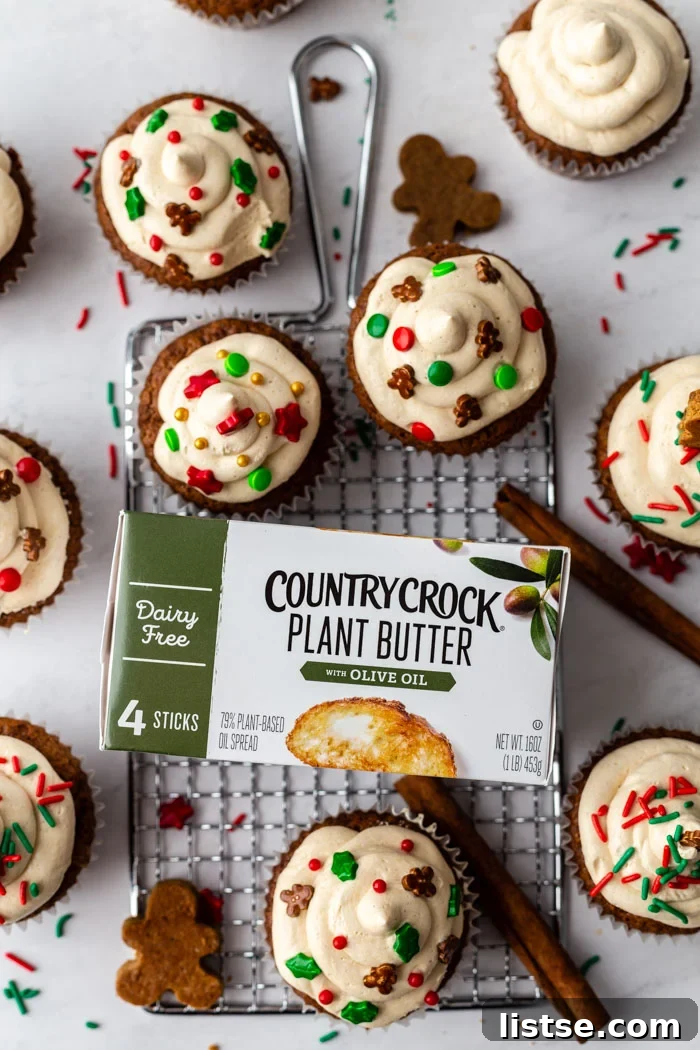 Spiced Gingerbread Cupcakes 3 Close-up of fluffy vegan gingerbread cupcakes adorned with gingerbread man sprinkles, accompanied by sticks of Country Crock Plant Butter, highlighting their plant-based goodness.
