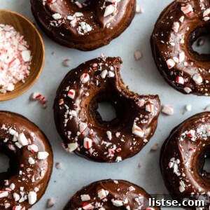 Top-down view of chocolate donuts with chocolate frosting and crushed peppermint on top.