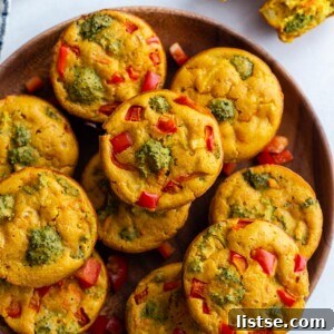 A high-angle shot of a rustic wooden plate filled with golden-brown vegan egg cups, vibrant with visible veggies.