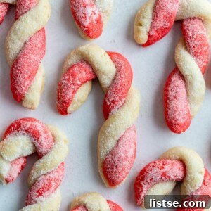 red and white sugar cookies that are twisted to look like candy canes. All laying on parchment paper