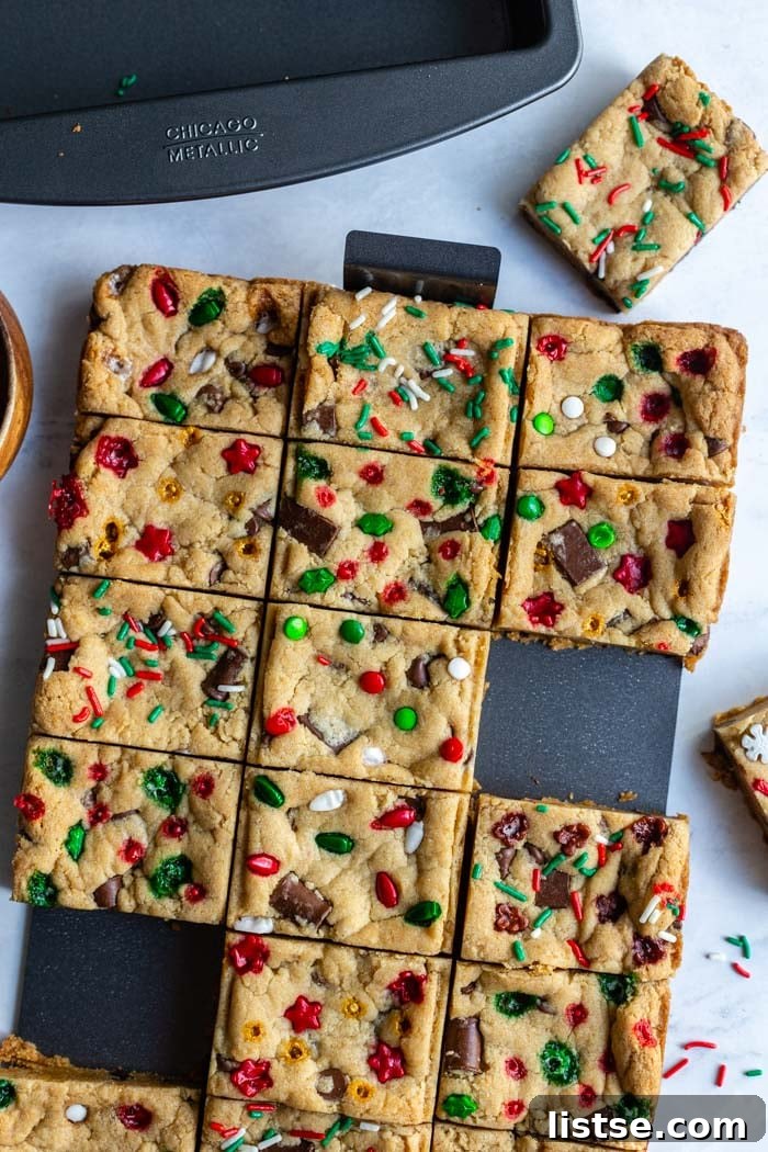 Gooey Chocolate Chip Squares 4 chocolate chip cookie bars in a slice solution pan with christmas sprinkles on top. several bars are taken off of the tray