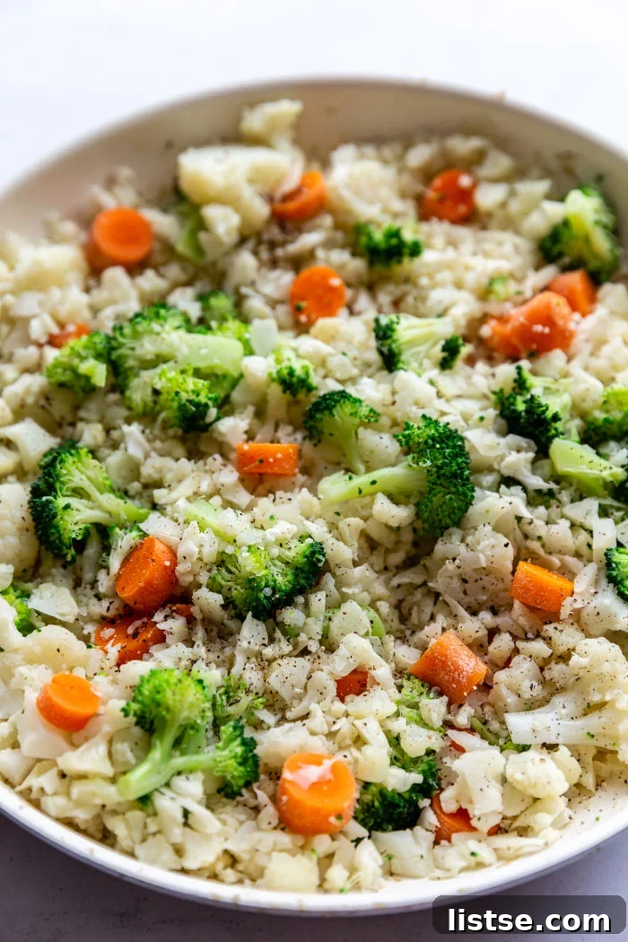Close-up of a skillet filled with perfectly cooked cauliflower fried rice, featuring a colorful mix of broccoli and carrots, ready to be served as a quick and healthy meal.