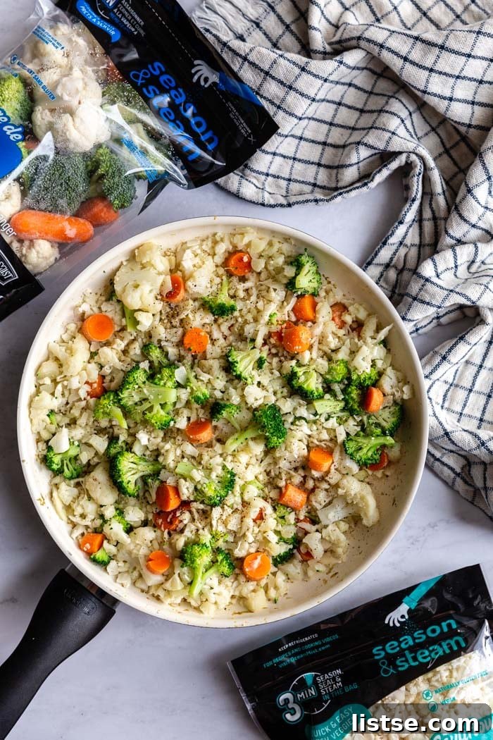 A vibrant skillet of cauliflower fried rice, generously mixed with broccoli and carrots, captured in a warm, inviting light.