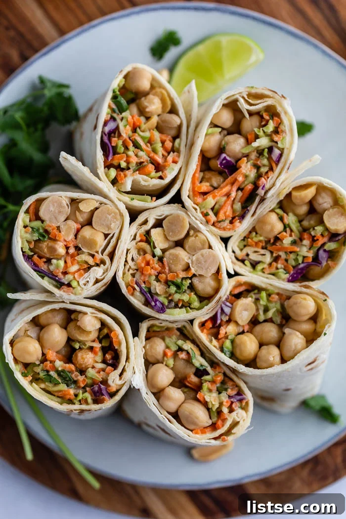 Savory Peanut Chickpea Wraps 2 Two peanut chickpea wraps, sliced in half, showcasing the vibrant chickpea and slaw filling, held together with toothpicks and presented on a plate.