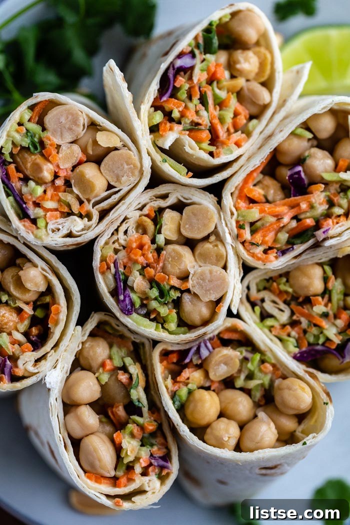 Savory Peanut Chickpea Wraps 5 Several chickpea and coleslaw wraps, cut in half and arranged artfully on a plate, showcasing their generous, colorful fillings.