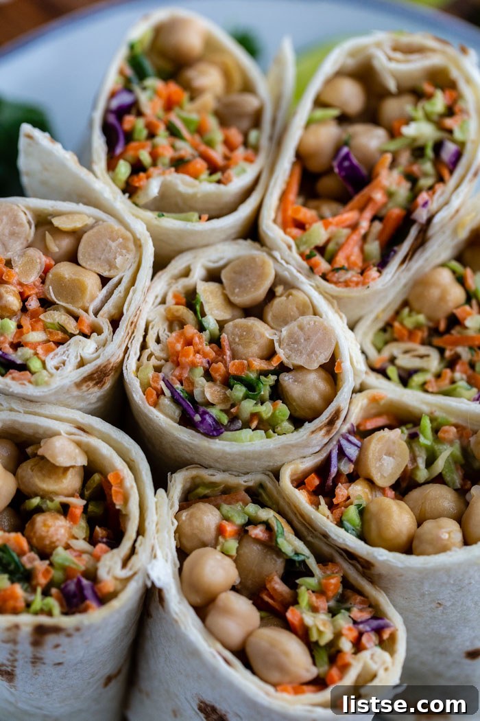 Savory Peanut Chickpea Wraps 7 A vibrant array of chickpea and coleslaw wraps, cut in half and standing upright on a plate, showcasing their rich and varied fillings.