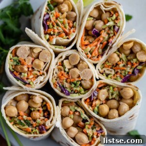 tortilla wraps filled with coleslaw mix and chickpeas. the wraps are cut in half and standing up on a plate so that you can see everything inside of them