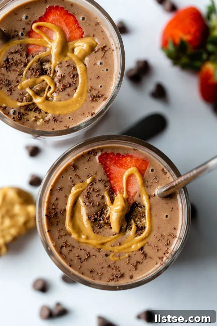 Chocolate Peanut Butter Smoothie in two glasses with strawberry, chocolate shavings, and peanut butter drizzle, showcasing its rich texture