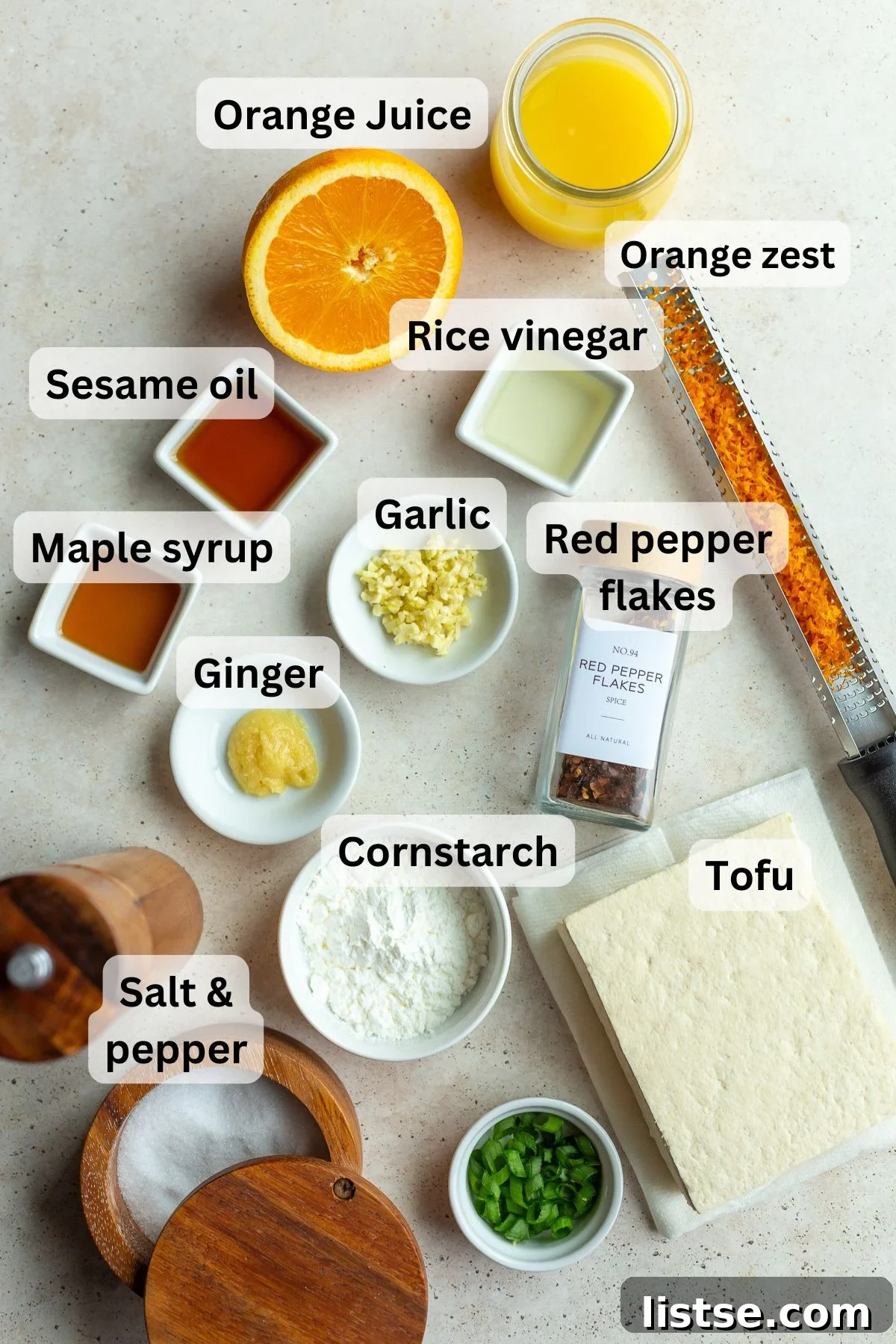 All the fresh ingredients laid out on a table, including tofu, oranges, ginger, garlic, and sauces, ready to make orange tofu.