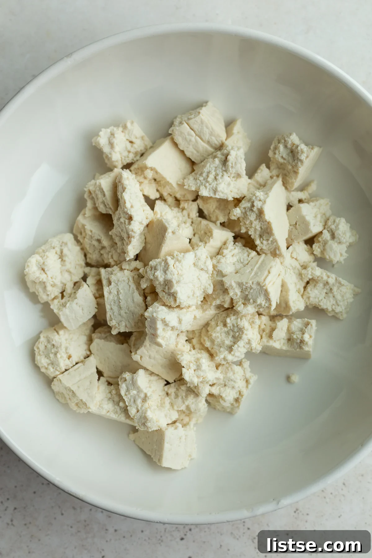 Pressed tofu torn into rustic chunks in a large mixing bowl.