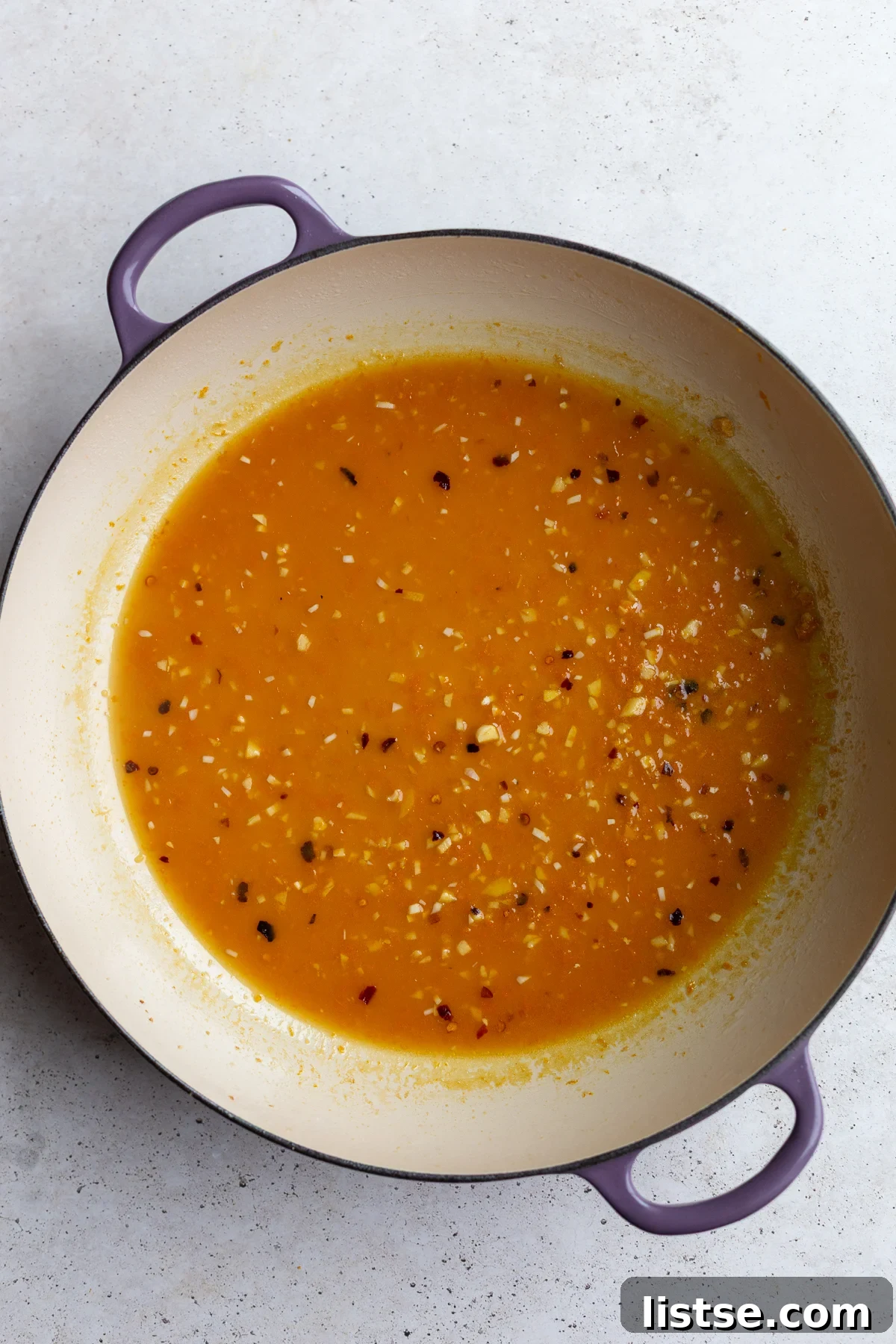 The orange tofu sauce simmering and thickening in the skillet.