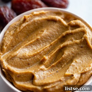 creamy date paste in a small bowl with fresh dates around the bowl