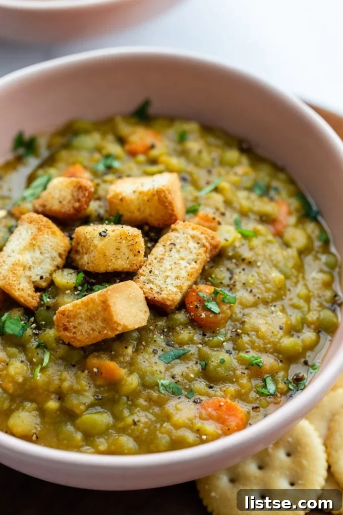 Close-up of creamy vegan pea soup served in a rustic bowl, accompanied by crunchy croutons, highlighting its rich texture.