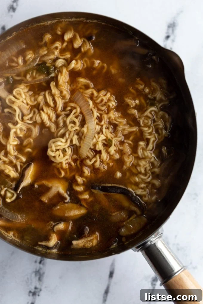 Wholesome Vegan Ramen Comfort 4 Making vegan ramen in a large pot, with ingredients like mushrooms, bok choy, and broth simmering