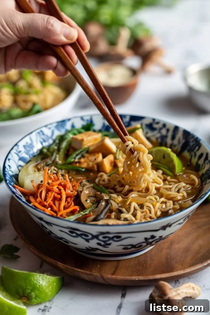 Wholesome Vegan Ramen Comfort 5 A hand lifting strands of vegan ramen noodles from a bowl with chopsticks, showing the rich broth and toppings
