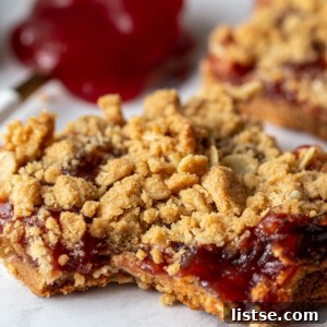 Peanut butter and jelly crumble bars with a spoonful of jelly in the background