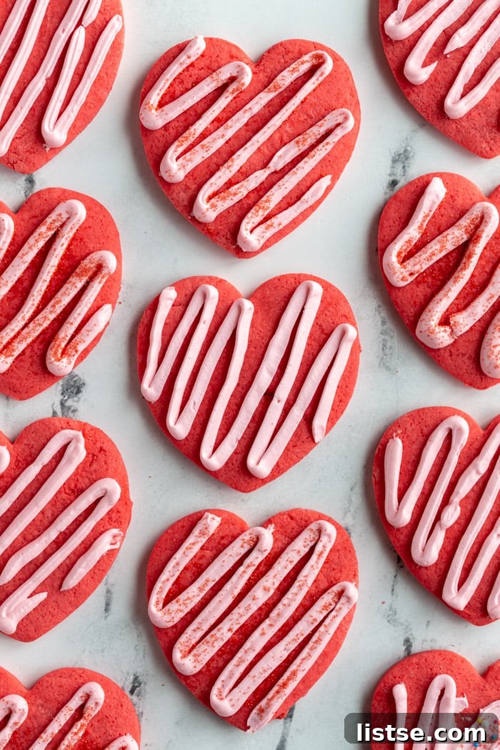 Red heart-shaped vegan cookies elegantly topped with a light pink zig-zag frosting, embodying the spirit of Valentine's Day.