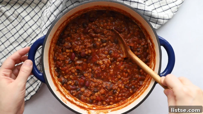 The finished lentil chili, thick and bubbling gently in a pot, ready to be served, promising warmth and deliciousness.