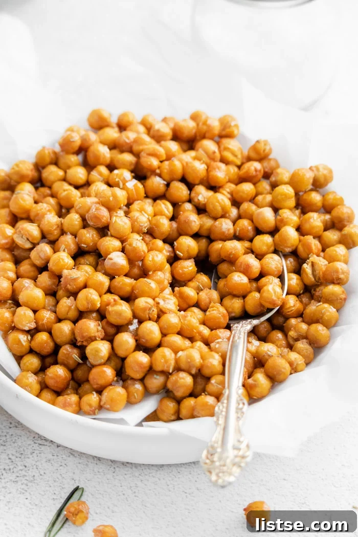 side shot of crispy chickpeas sitting in a shallow white bowl with a spoon scooping up some of the chickpeas