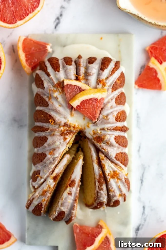 Zesty Vegan Grapefruit Loaf 9 Iced grapefruit loaf topped with slices of grapefruit and more grapefruit around the loaf. some slices taken out from the loaf