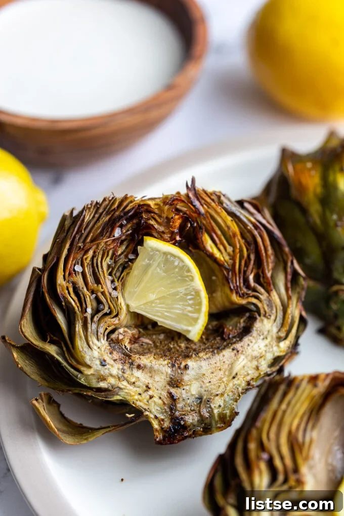 Crispy air-fried artichoke halves garnished with a lemon slice and served with a white dipping sauce.