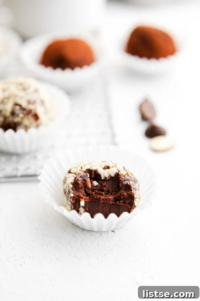 Amaretto Dream Truffles 7 Assortment of Amaretto Chocolate Truffles, beautifully coated in nuts, presented in mini muffin liners with more truffles in the background, ready to be served.