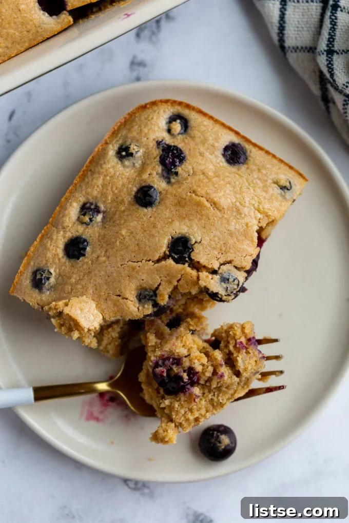 Baked Oats Double the Delight 3 baked oatmeal on a plate with blueberries on top and a bite taken out by a fork