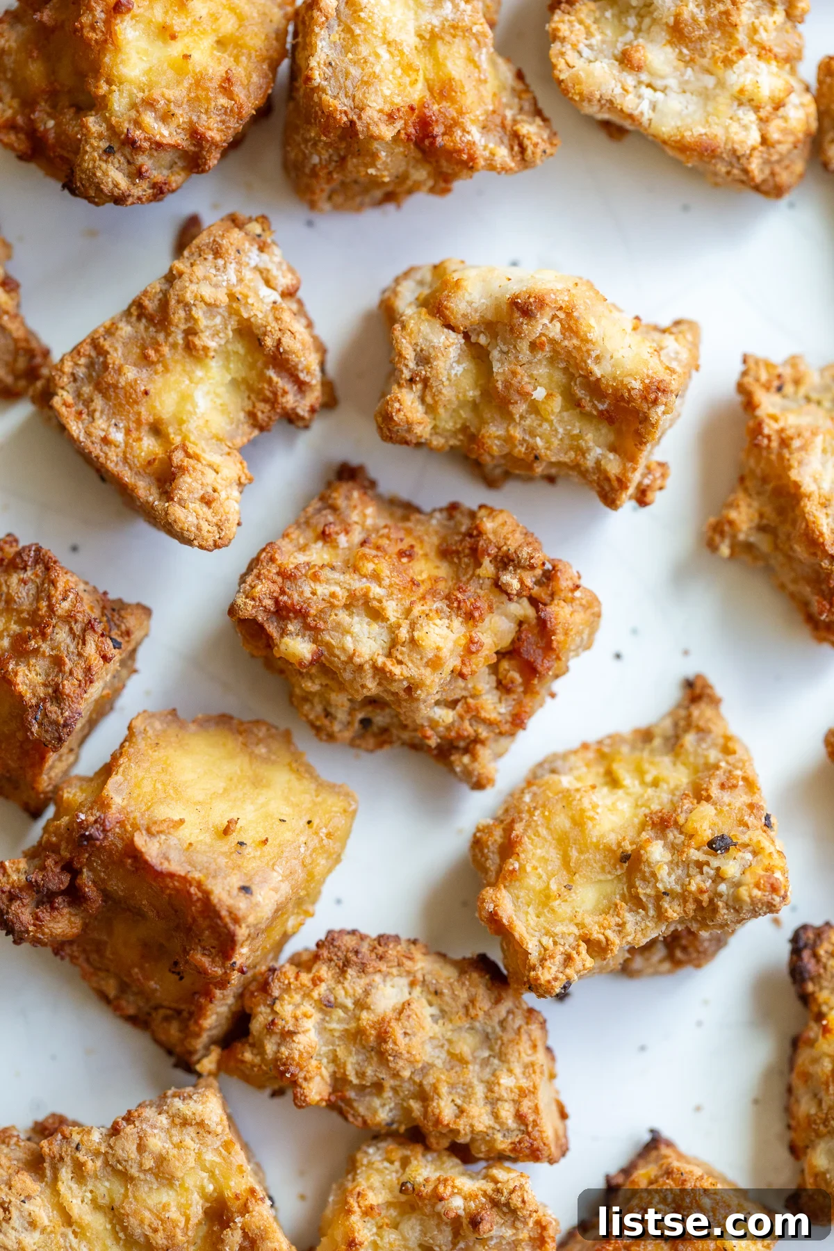 Golden-brown, crispy air fryer tofu pieces served on a simple white plate, highlighting their perfectly crunchy texture.