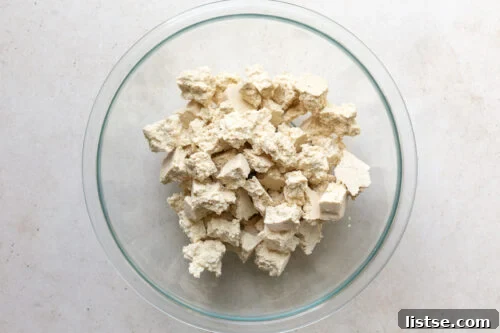 Torn tofu chunks placed in a large bowl, ready for seasoning.