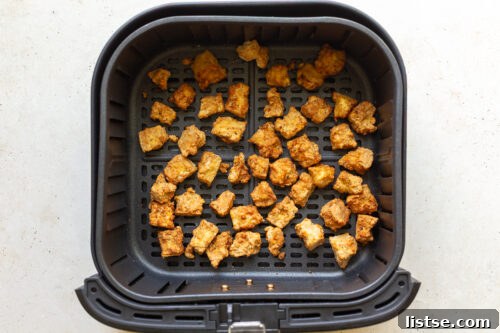 Crispy air fryer tofu cooking in the air fryer basket.