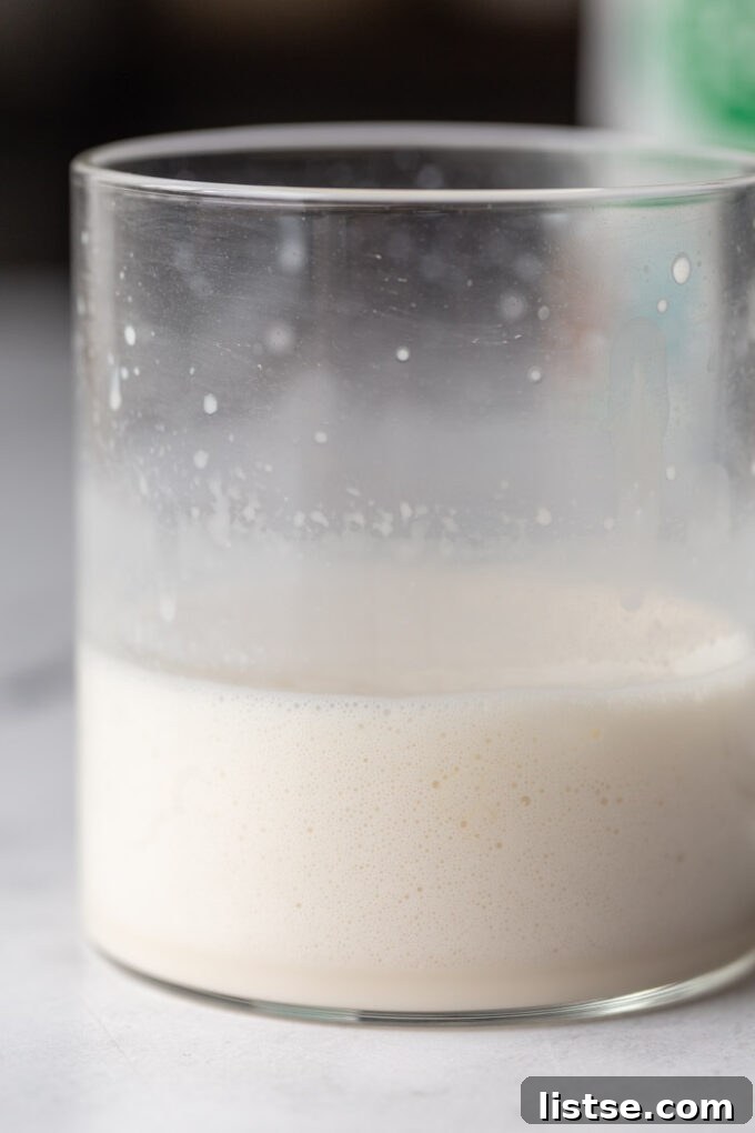 Close-up shot of a clear mug filled with freshly frothed plant-based milk, ready for coffee.