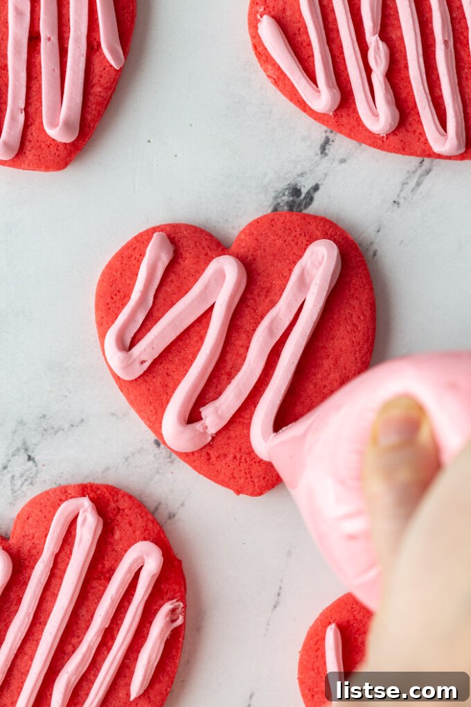 A heart-shaped sugar cookie being delicately frosted with smooth pink icing, ideal for Valentine's Day.