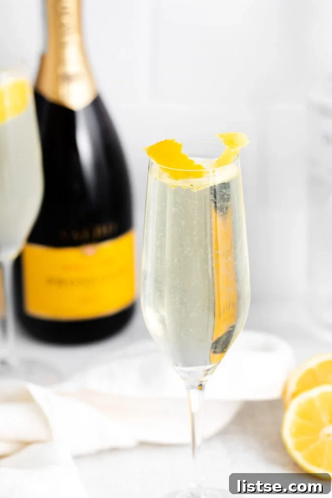 Sparkling French 75 cocktail in a flute next to a bottle of chilled champagne