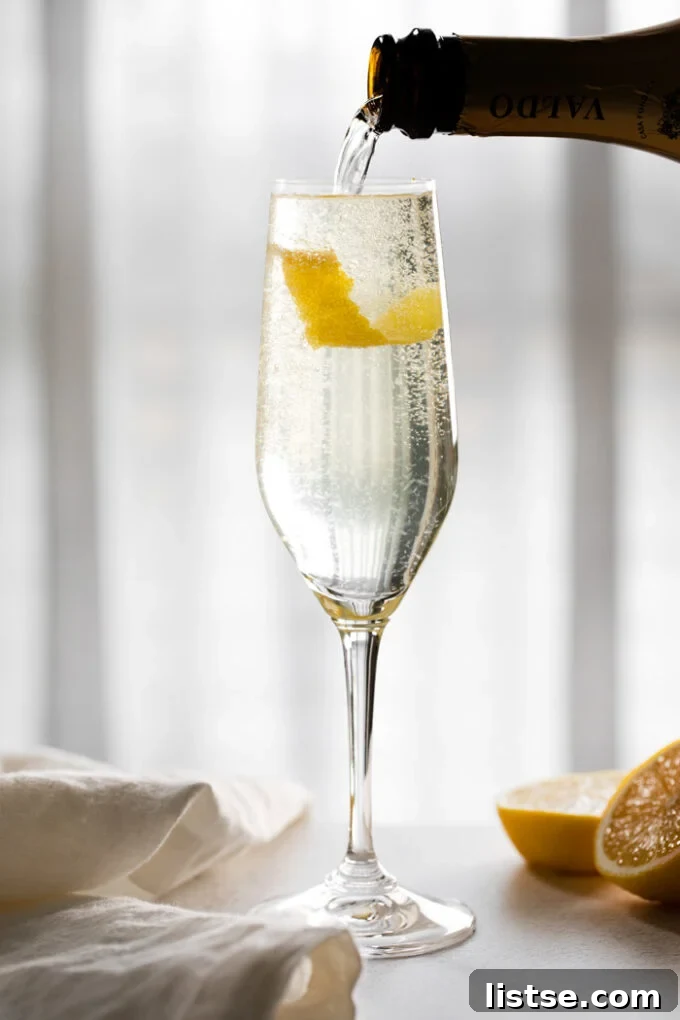 Pouring champagne into a glass containing a pre-made gin and lemon mixture with a lemon twist