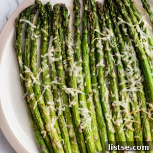 Air fryer asparagus topped with parmesan cheese on a serving plate