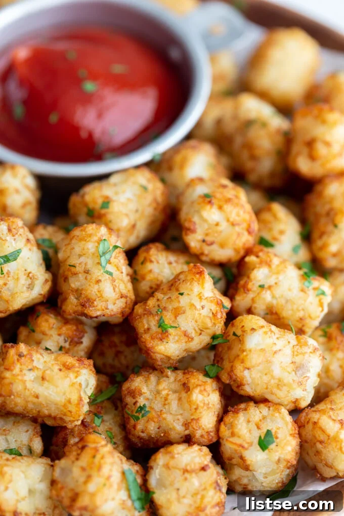 wood plate lined with parchment paper and topped with crispy tater tots and a bowl of ketchup