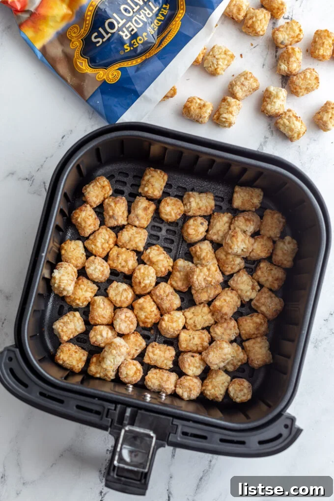 frozen tater tots in air fryer with the bag of tots in the top of the frame