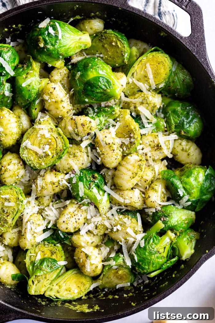 Vibrant Brussels Sprouts Pesto Gnocchi 2 A perfectly cooked Brussels Sprouts Pesto Gnocchi dish in a black cast iron skillet, generously topped with fresh cheese.