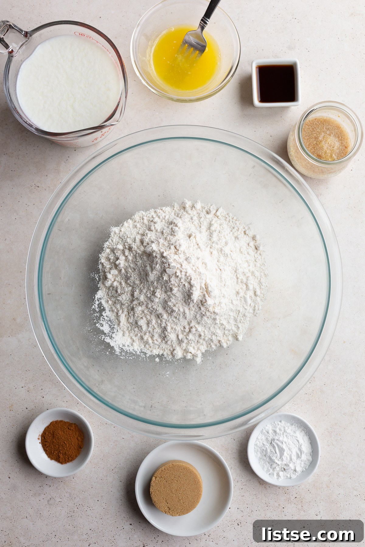 Individual bowls showcasing the essential dry ingredients: all-purpose flour, plant-based milk, granulated sugar, and ground cinnamon, ready for mixing.