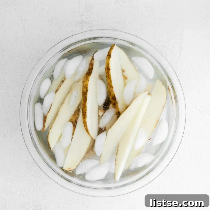 Raw potato slices soaking in an ice bath to achieve maximum crispiness