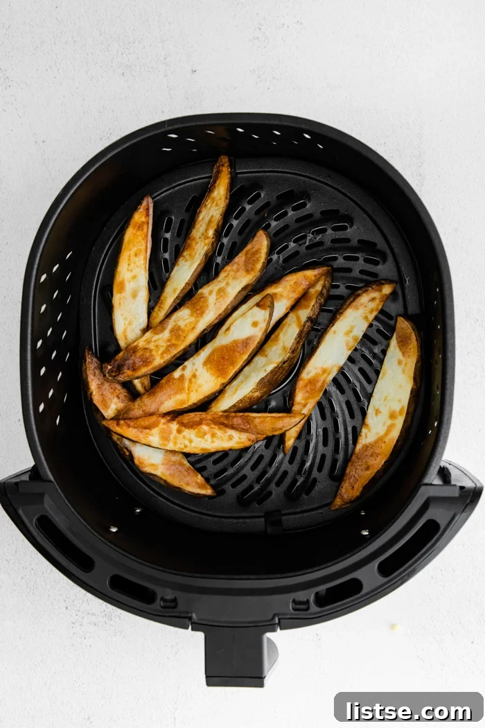 Freshly cooked crispy potato wedges resting in an air fryer basket