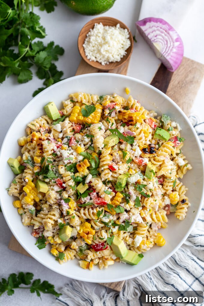 Vibrant Elote Pasta Salad 4 Large bowl of Mexican Street Corn Pasta Salad, generously garnished with fresh cilantro, crumbled cotija cheese, and finely diced red onion, ready for serving at a summer gathering.
